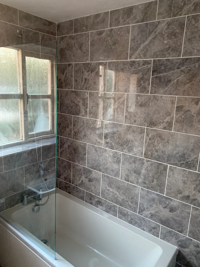 Grey stone tiled bathroom with bath and shower screen